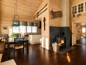 Un intérieur de chalet chaleureux comprenant un coin repas, une cuisine, une cheminée et un porte-skis.