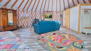 A spacious room with a large bed, a blue sofa, and a colorful rug. - Enchanting yurt in secluded mountain view setting (Swan Valley)