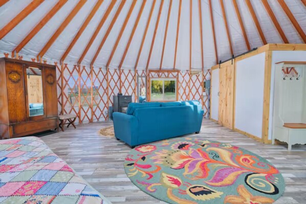 A spacious room with a large bed, a blue sofa, and a colorful rug.