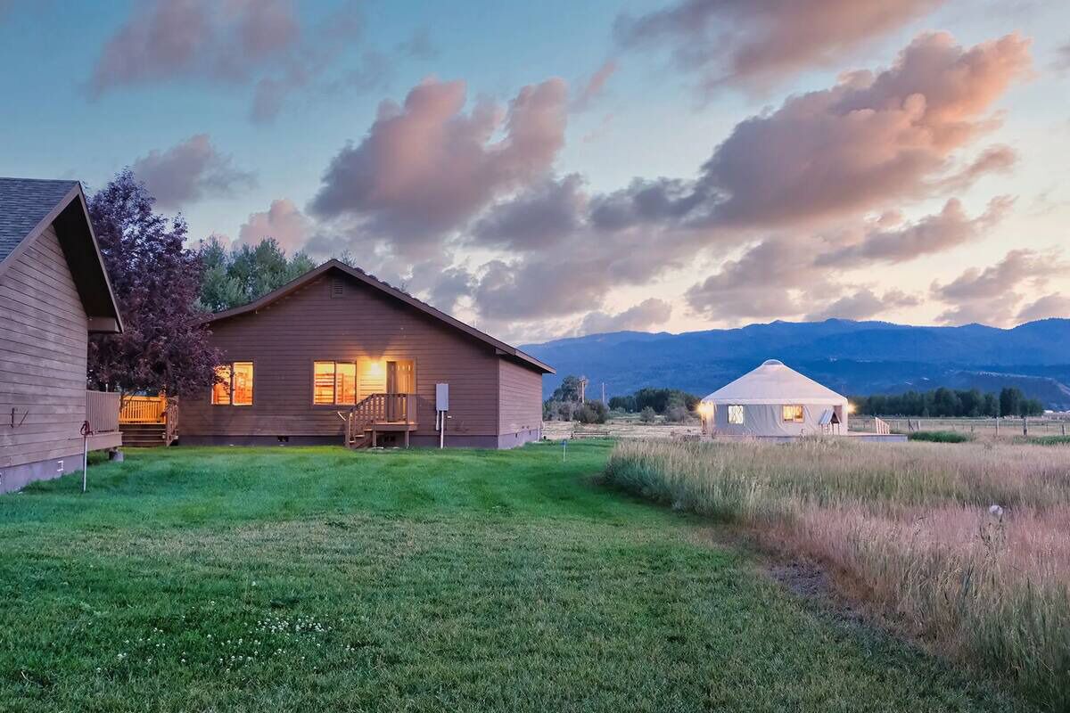 Une maison à deux étages, dotée d’une pelouse bien entretenue et d’une yourte visible au fond.
