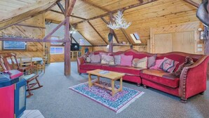 Ein gemütliches Loft-Zimmer mit rotem Sofa, Holztisch und einer Deckenleuchte.