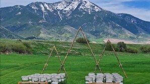 Hochzeitliche Dekoration mit in Reihen angeordneten Stühlen vor einer Bergkulisse.
