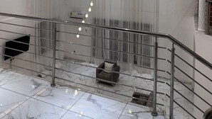 Ett rymligt interiört utrymme med ett marmorgolv, en trappa med metallräcken och en modern takdesign med infälld belysning.
