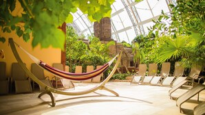 Un hamac dans un espace intérieur bien éclairé, avec des chaises et des plantes.