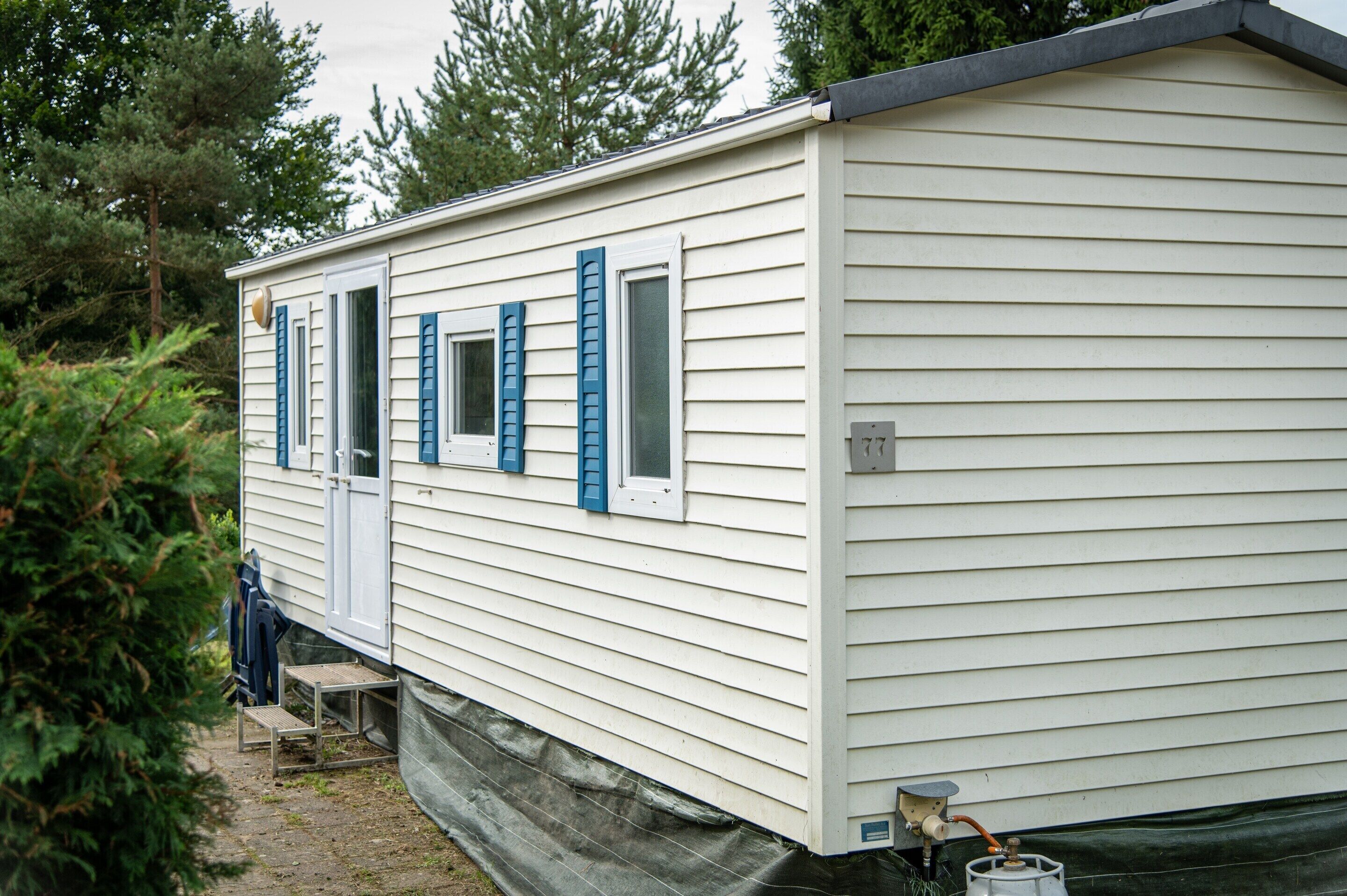 A mobile home with a door, windows, and a small outdoor area with steps.