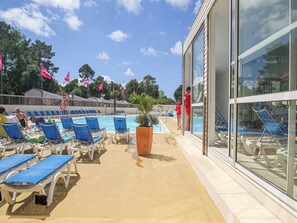 Et poolområde med blå liggestole, en pool og en bygning med store vinduer.