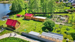 An aerial view of a residential area with a lake, houses, and a sports field. - Mobile Home by the Lake Beach (Malechowo)