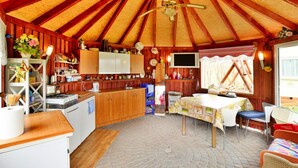 A cozy kitchen with wooden beams, a central island, and a dining area with a table and chairs. - Mobile Home by the Lake Beach (Malechowo)