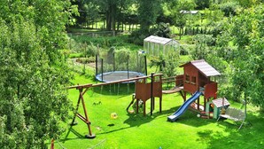 A playground with a swing set, slide, and climbing structure. - Mobile Home by the Lake Beach (Malechowo)