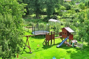 Een speeltuin met een schommel, een glijbaan en een klimstructuur.