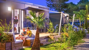 A modern outdoor seating area with a wooden bench and a palm tree. - VIP Mobile Home With Terrace (Vendres)