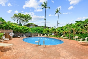 A swimming pool surrounded by lounge chairs and a stone wall.