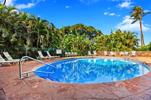 A swimming pool with lounge chairs and palm trees in the background.