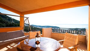 Ein Balkon mit einem runden Tisch, zwei Stühlen und einer Hängeschaukel.