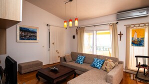 Ein Wohnzimmer mit einer Couch, einem Couchtisch, einem Fernseher und einem Bild an der Wand.