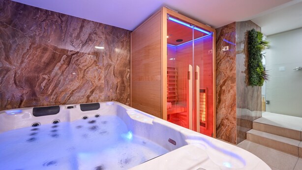 A modern spa room with a hot tub, wooden sauna, and a glass shower enclosure. - Villa Vinea by Villas Guide (Novakovec)