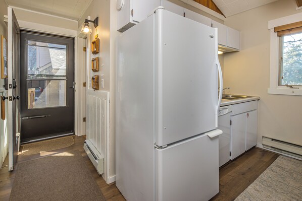 A compact kitchen with a white refrigerator, a small sink, and a window.