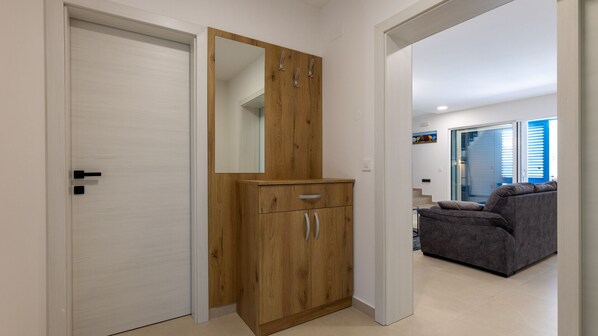 A hallway with a wooden wardrobe, a white door, and a grey sofa in the background.