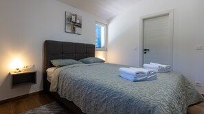 Een slaapkamer met een bed, nachtkastje en een deur.