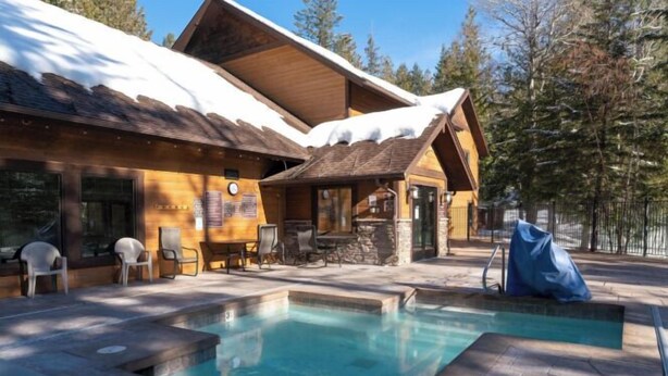 A lodge with a pool, outdoor seating, and a stone fireplace. - New! Spruce Nest Cabin - Alpine Skiing | Community Pool and Hot Tub (Whitefish)