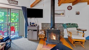 A cozy living room with a fireplace, a television, and a wooden ceiling. - New! Spruce Nest Cabin - Alpine Skiing | Community Pool and Hot Tub (Whitefish)