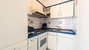 Eine kleine Küche mit weißen Schränken, einer blauen Arbeitsplatte, einem eingebauten Backofen und einer Kaffeemaschine.