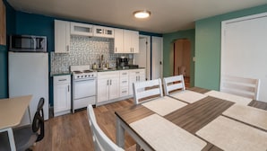 A compact kitchen with white cabinets, a microwave, stove, and a dining area with a table and chairs. - Charming 3-bedroom/2 Bath Ranch Style Home minutes to everything in Kansas City (Kansas City)