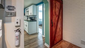 A kitchen with white cabinets, a red door, and a fire extinguisher mounted on the wall. - Charming 3-bedroom/2 Bath Ranch Style Home minutes to everything in Kansas City (Kansas City)
