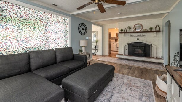A living room with a sectional sofa, a fireplace, and a decorative wall. - Charming 3-bedroom/2 Bath Ranch Style Home minutes to everything in Kansas City (Kansas City)