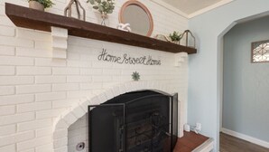 A fireplace with a brick surround and a mantel above it. - Charming 3-bedroom/2 Bath Ranch Style Home minutes to everything in Kansas City (Kansas City)