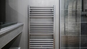 Un porte-serviettes métallique dans une salle de bain dotée d’une cabine de douche en verre.