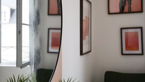 Une pièce avec une fenêtre, un canapé vert et des œuvres d’art encadrées accrochées au mur.