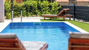 A rectangular swimming pool with a clear blue water surface, surrounded by a small grassy area and a black fence. - Villa Stjepan Zep (Kvarner - Županje) (Županje)