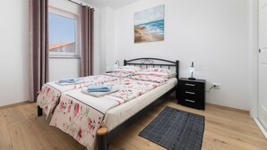 A bedroom with a bed, a nightstand, a painting, and a window with curtains. - Villa Stjepan Zep (Kvarner - Županje) (Županje)