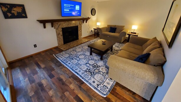 Ein Wohnzimmer mit Kamin, einer Couch, einem Couchtisch und einem an der Wand befestigten Fernseher.