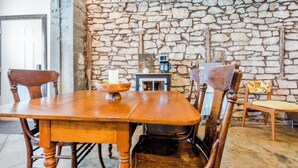 Un coin repas avec une table et des chaises en bois, un mur en pierre et une machine à café.