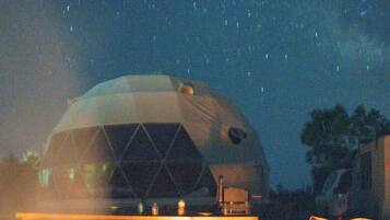 A geodesic dome structure with a fire pit and outdoor seating.