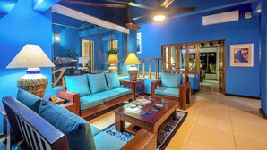 A room with a blue wall, a ceiling fan, a wooden coffee table, and a sofa.