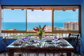 A dining table set for four with a view of the sea and buildings in the background.