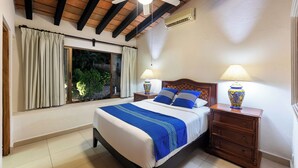 A bedroom with a bed, two bedside tables, a ceiling fan, and a window with curtains.
