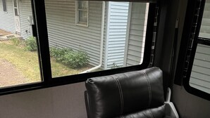 A compact RV interior with a small seating area featuring a cushioned bench and a wooden table. - Quaint RV with AC can be picked up in Berrien Springs 29ft a slide out also. (Berrien Springs)