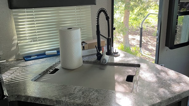 A kitchen with a sink, a faucet, a window with blinds, and a door with a handle. - Quaint RV with AC can be picked up in Berrien Springs 29ft a slide out also. (Berrien Springs)
