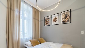 A modern bedroom with a bed, a chair, and a window with curtains.