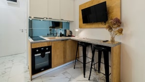 A modern kitchen with white cabinets, a built-in oven, a sink, and a small bar area with stools.