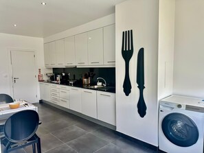 A modern kitchen with white cabinets, a sink, and a Samsung washing machine.