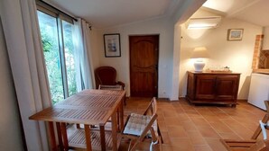 A dining area with a wooden table and chairs, a wooden cabinet, and a door leading to another room.