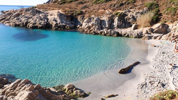 A beach with clear turquoise water, rocky terrain, and a few people on the shore. - Mobile home in Ramatuelle - plaine de Pampelonne (Ramatuelle)