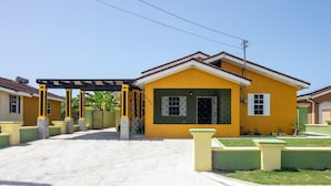 Un edificio giallo con ingresso coperto e un piccolo prato.