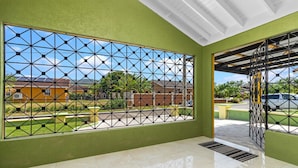 Una stanza con un'ampia finestra caratterizzata da un motivo geometrico, una parete verde e un pavimento piastrellato.