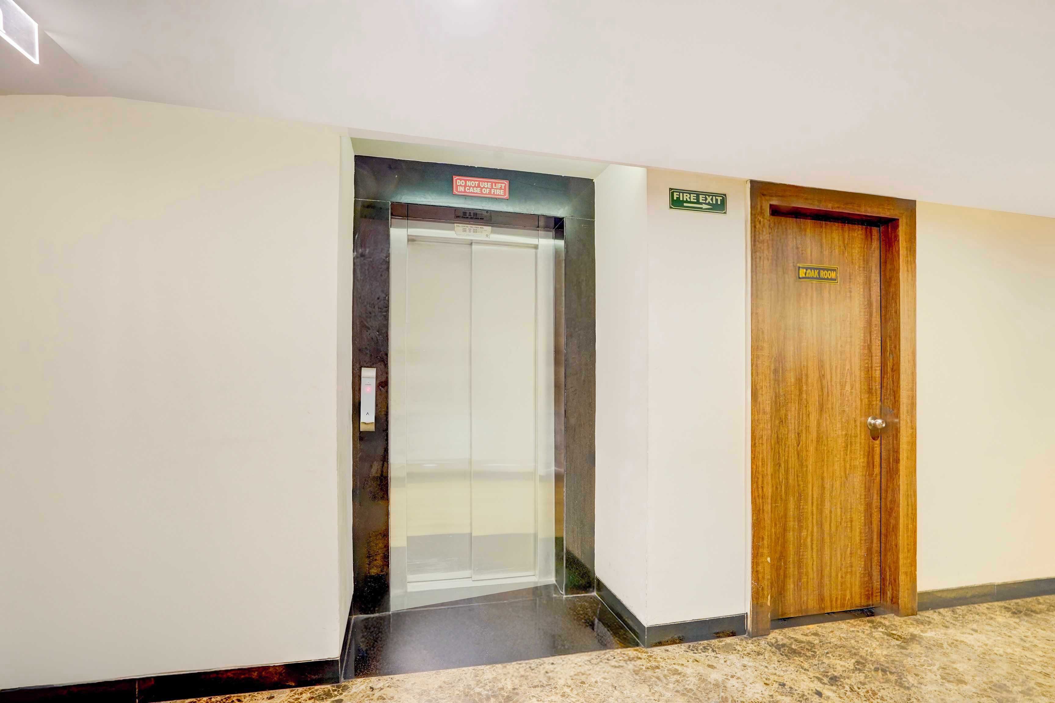 Um elevador, um sinal de saída de incêndio e uma porta de quarto com uma placa.